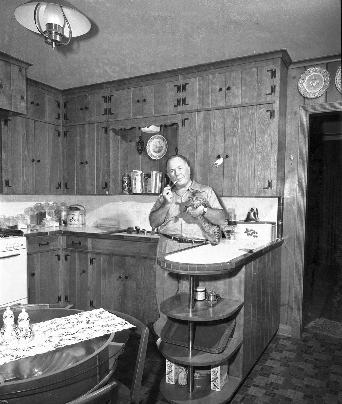 Aug. 27, 1954: Mr. Rhodes in kitchen holding a cat.