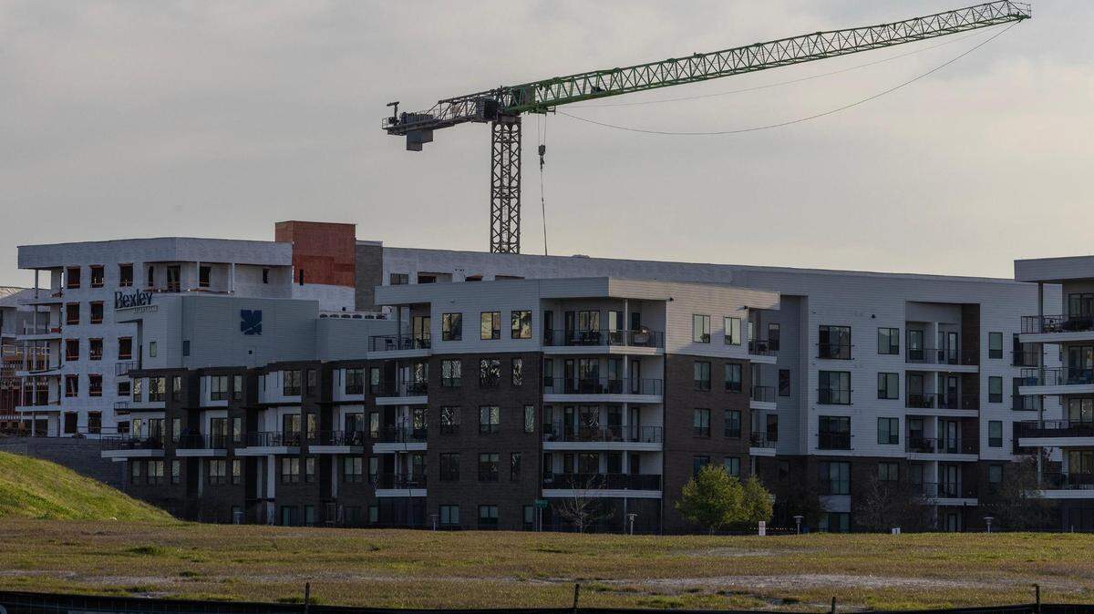 A construction crane towers over a half built apartment complex. 