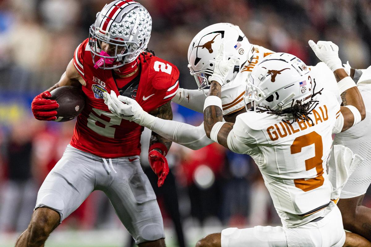 Ohio State wide receiver Emeka Egbuka (2) catches a pass and avoids a tackle from Texas defenders in the first quarter of the College Football Playoff semifinal game between Ohio State and Texas at AT&T Stadium in Arlington on Friday, Jan. 10, 2025.