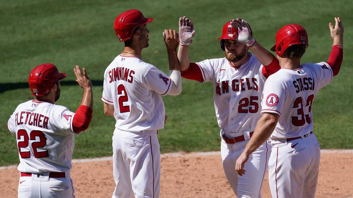 Los Angeles Angels’ Jared Walsh (25) celebrates with David Fletcher, left, Andrelton Simmons and Max Stassi, right, who all scored on Walsh’s grand slam during the fourth inning of Monday’s 8-5 victory over the Texas Rangers in Anaheim, Calif.
