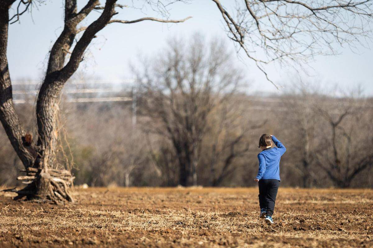 Uriah White, 7, runs out on the newly plowed fields on the 85-acre family farm in Burleson.