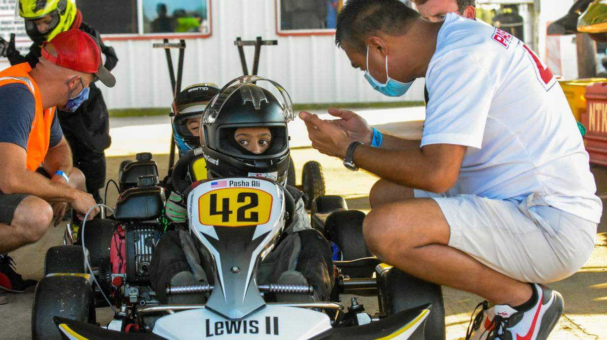 Former professional race car driver Nur Ali kneels down to give some advice to his 6-year-old son Pasha, who is following in his dad’s tire tracks as one of the country’s most accomplished young go-kart drivers.