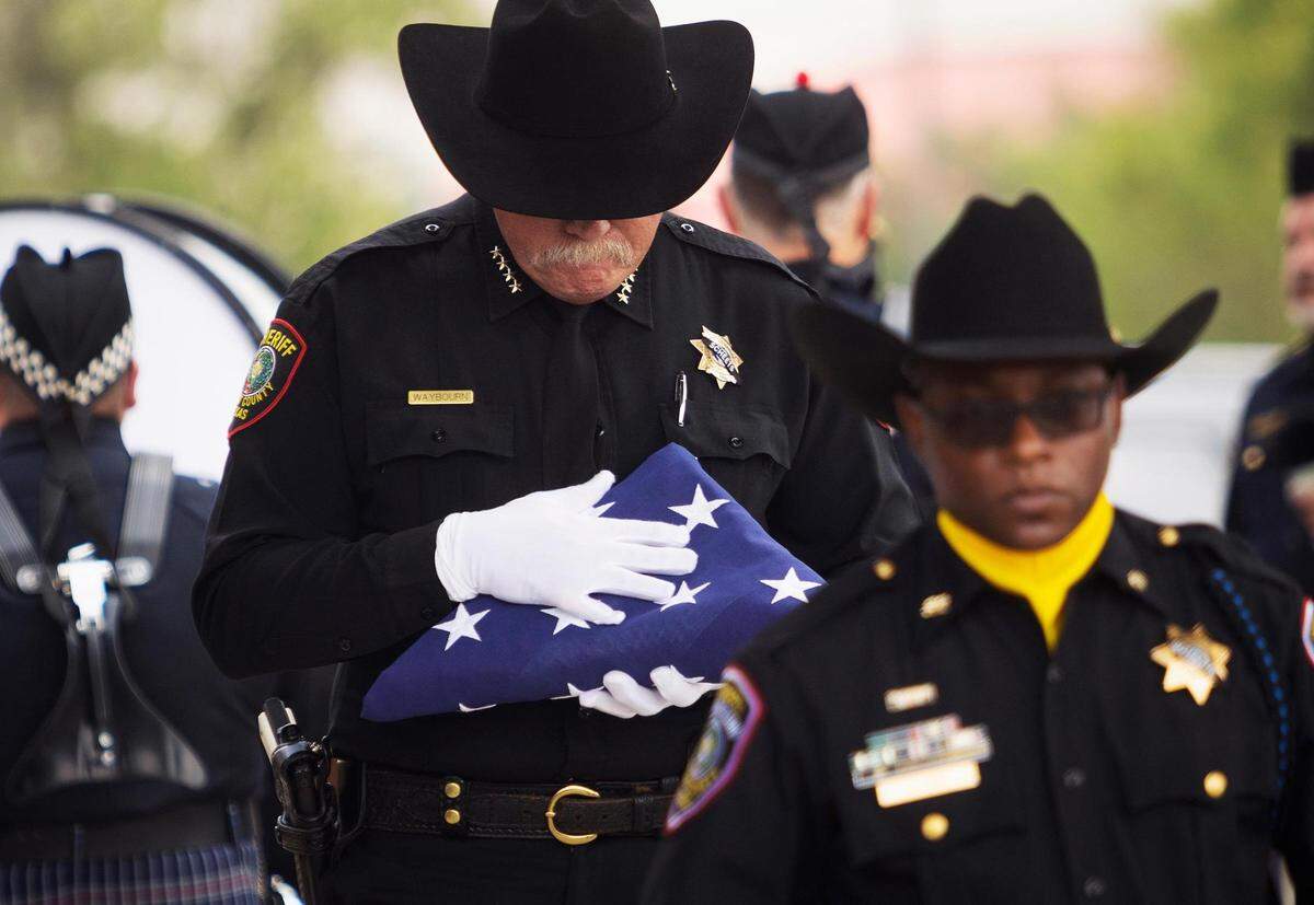 Tarrant County Sheriff Bill Waybourn carries a flag to give to the family of Tarrant County Deputy Billy W. Scheets, 55, during his funeral on Thursday at Met Church in Fort Worth. “We said goodbye to a hero,” said Waybourn.