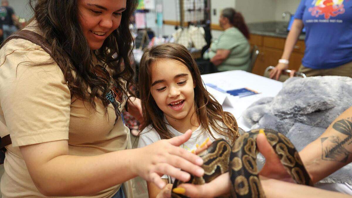 Azle resident Haley Edmunds and her daughter, Raven, 6, pet an African ball python at the Children’s Aquarium Dallas booth while attending the Texas Homeschool Expo at the Grapevine Convention Center on Friday, June 9, 2023, in Grapevine. Edmunds began homeschooling last year when Raven reached first grade and plans to continue.