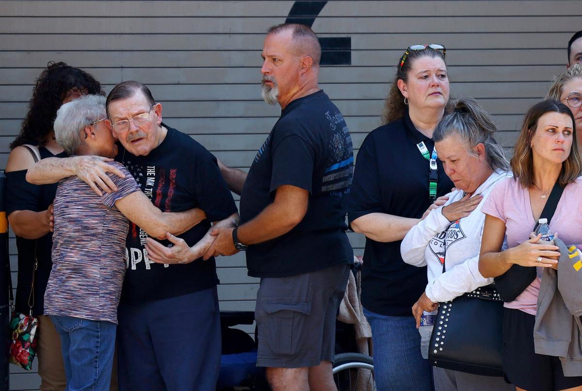 Family members are comforted as law enforcement, city officials, medical staff, family and friends line up along St. Louis Avenue for the procession to transport Fort Worth Police Department Sgt. Billy Randolph’s body from John Peter Smith Hospital to the medical examiner’s office on Monday, Aug. 12, 2024. Randolph was killed earlier in the morning after being hit by a vehicle while working at an accident scene on I-35W.