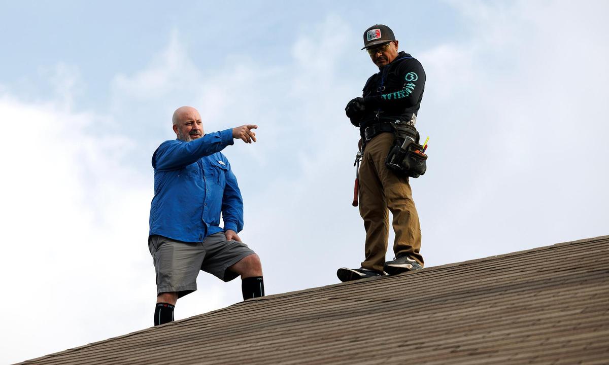 Frank McArthur, owner of Focus Contracting Services, left, and Julio Rodriguez work on a roof on Wednesday, March 26, 2025, in Keller.