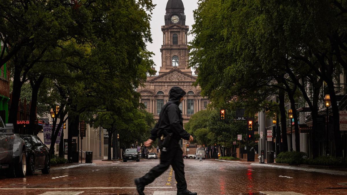Sundance Square security guard Alex Arabie walks the crosswalk in the rain on West 3rd Street at Sundance Square in downtown Fort Worth on Tuesday, Sept. 3, 2024.