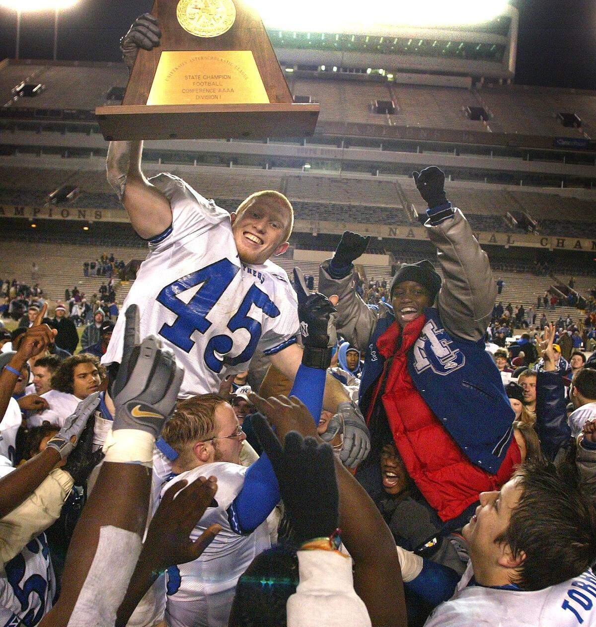 North Crowley fullback and linebacker Tyson Reich holds up the championship trophy as players and fans lift him into the air after the win. North Crowley wins 20-6. Texas high school football state championship game. North Crowley High vs Bay City High for the 4A Division 1 state title at Kyle Field in College Station, Texas, Saturday, December 13, 2003. (Star-Telegram/Ron Jenkins) High school football