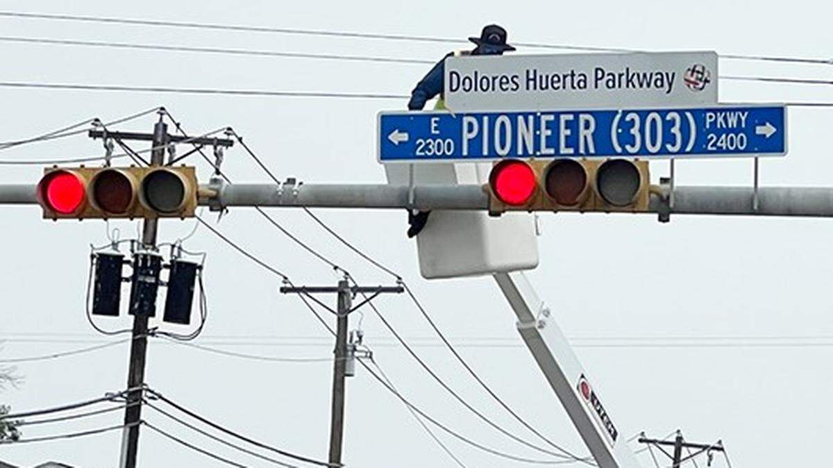 A city of Arlington worker unveils a Dolores Huerta street topper on May 27.