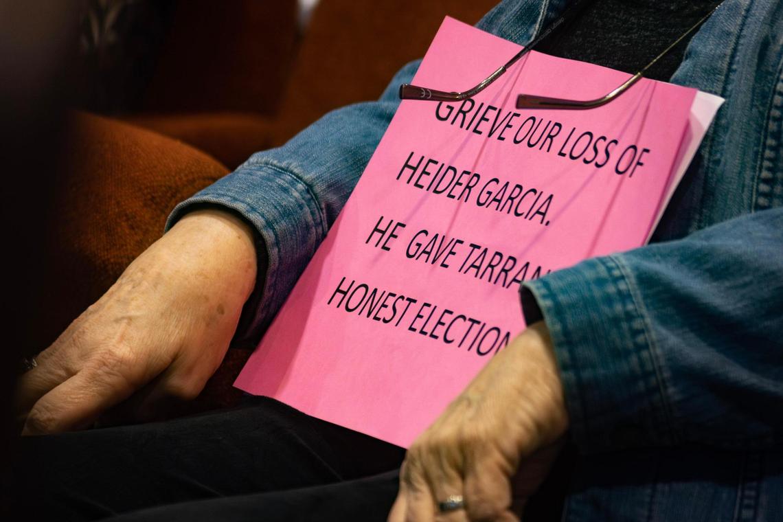 Carol Cordell props up a sign regarding the resignation of Tarrant County elections chief Heider Garcia during an Elections Commission meeting on Tuesday.