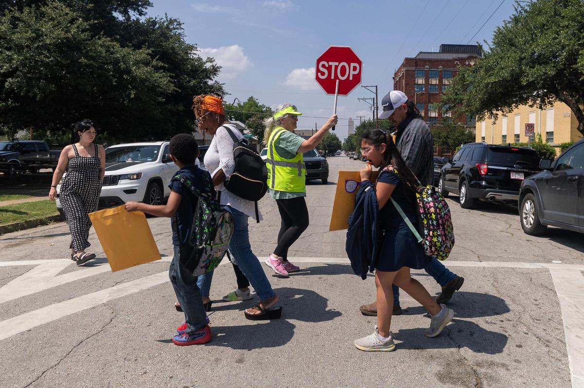 Fort Worth ISD crossing guard Melissa Leslie, center, helps families cross the street after the students’ final day of the school year at De Zavala Elementary School on May 22. The school is located in Fort Worth’s Fairmount neighborhood.