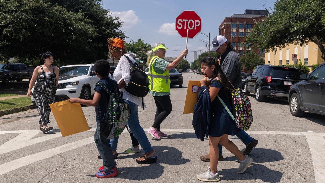 Fort Worth ISD crossing guard Melissa Leslie, center, helps families cross the street after the students final day of the school year at De Zavala Elementary School in Fort Worth on Thursday, May 22, 2025. Fort Worth ISD continues to struggle with chronic absenteeism five years after COVID school shutdowns ended.