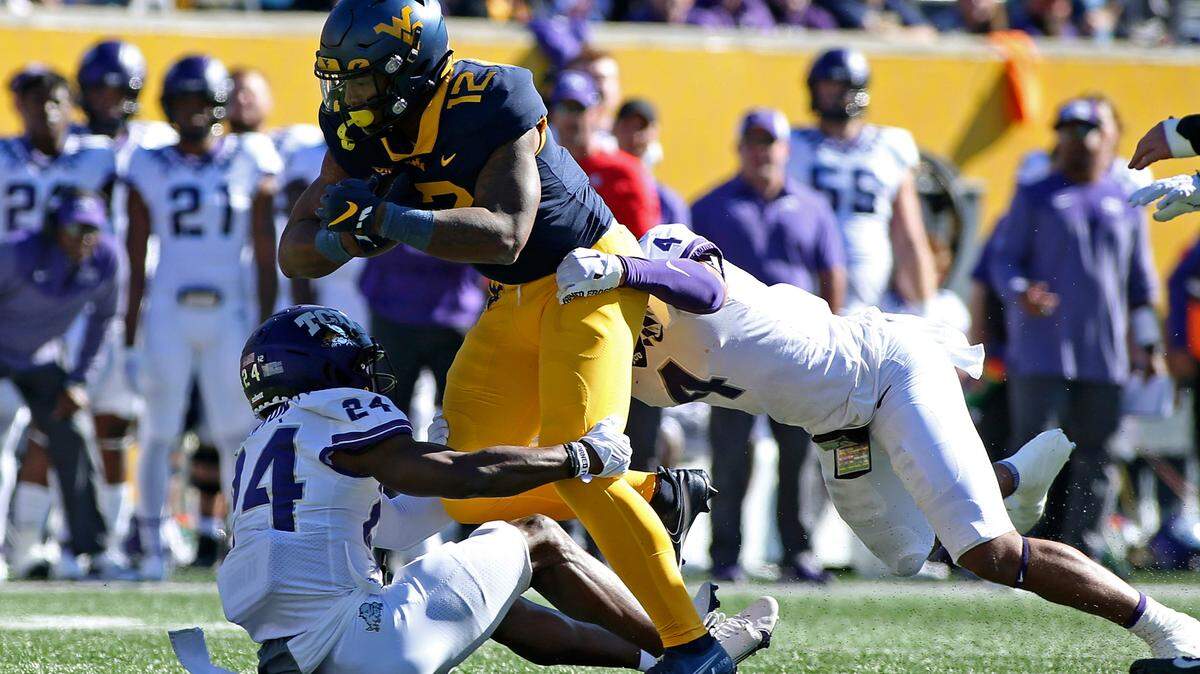 West Virginia tight end CJ Donaldson (12) is tackled TCU cornerback Josh Newton (24) and safety Namdi Obiazor (4) during Saturday’s game in Morgantown, W.Va.