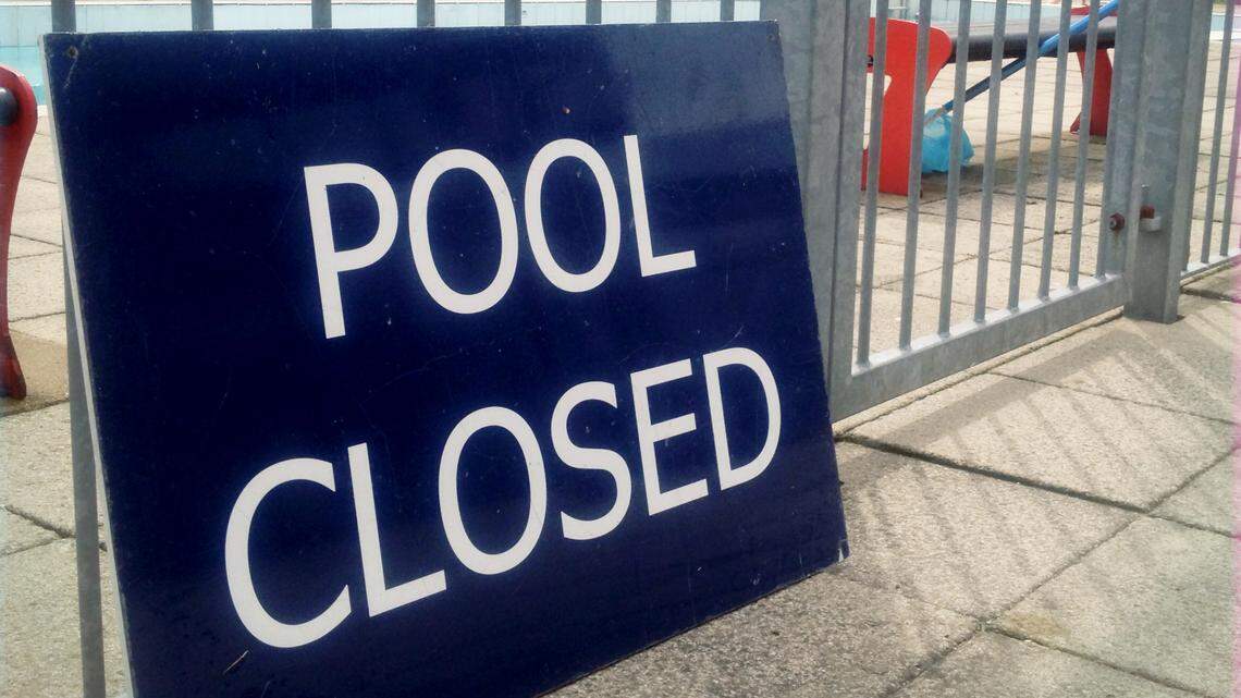 A closed sign on an outdoor public swimming pool.