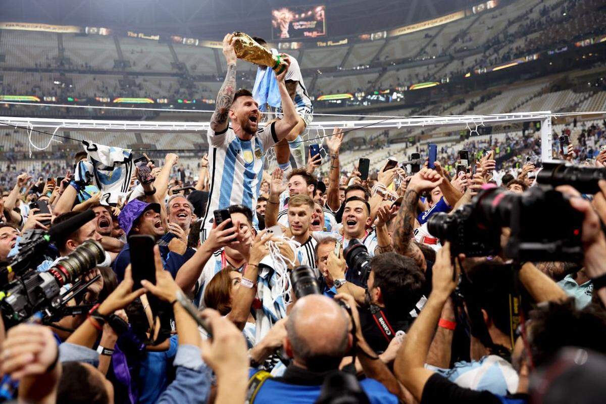 LUSAIL CITY, QATAR - DECEMBER 18: Lionel Messi of Argentina celebrates with teammates and the FIFA World Cup Qatar 2022 Winner's Trophy after the team's victory during the FIFA World Cup Qatar 2022 Final match between Argentina and France at Lusail Stadium on December 18, 2022 in Lusail City, Qatar. (Photo by Clive Brunskill/Getty Images)