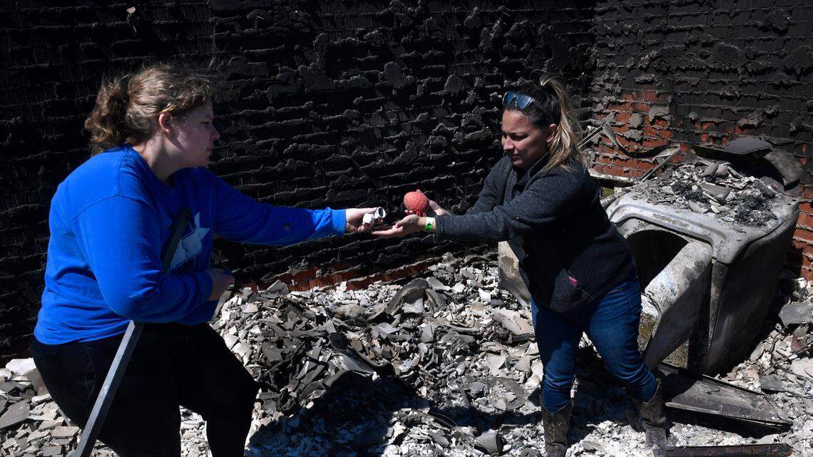 Bre Riggs, left, takes ceramic decorations from Priscilla Maynard, who had retrieved them from the surrounding ash of the home of their friends Raquel and Cruz Robles on Friday, March 18, 2022, in Eastland County, Texas. The house burned the day before in Eastland County’s Kidd Fire. (Ronald W. Erdrich/The Abilene Reporter-News via AP)
