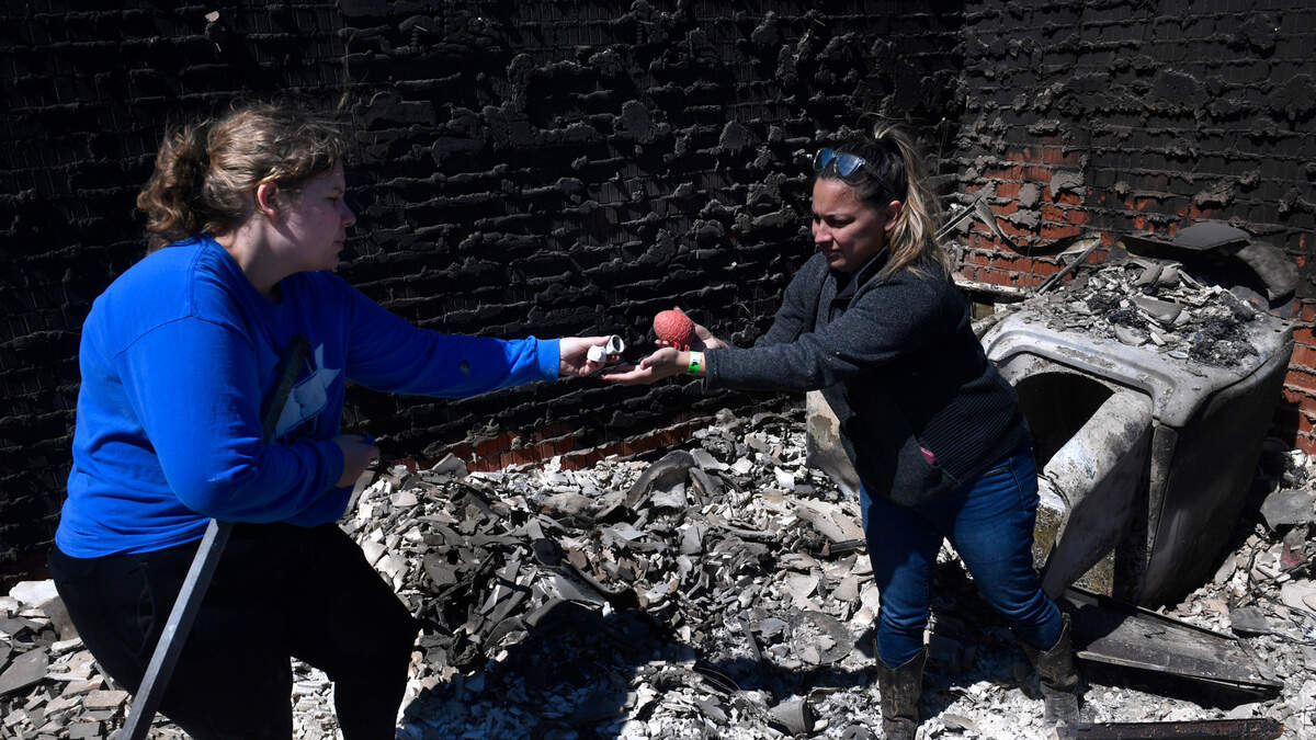 Bre Riggs, left, takes ceramic decorations from Priscilla Maynard, who had retrieved them from the surrounding ash of the home of their friends Raquel and Cruz Robles on Friday, March 18, 2022, in Eastland County, Texas. The house burned the day before in Eastland County’s Kidd Fire. (Ronald W. Erdrich/The Abilene Reporter-News via AP)