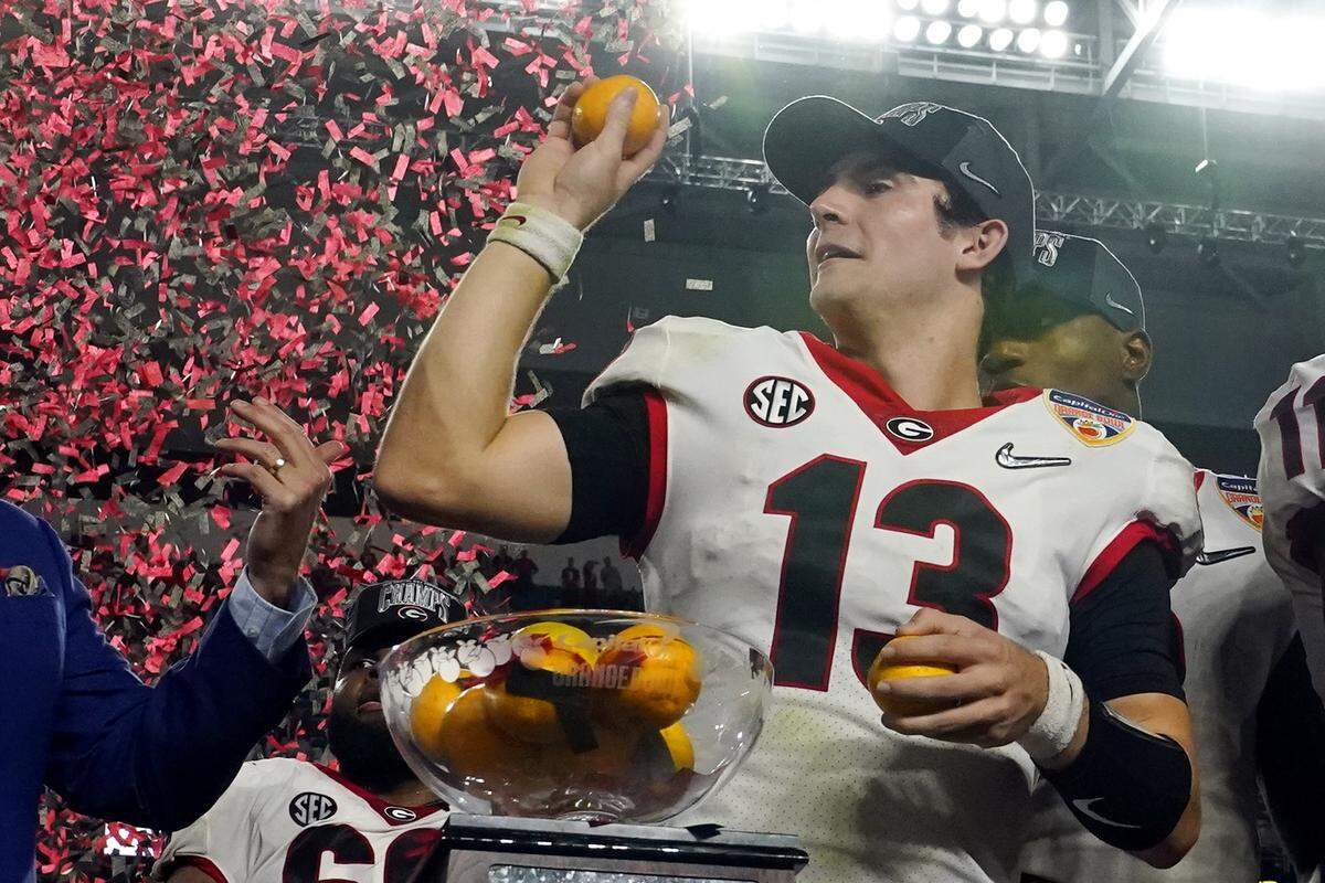 Georgia quarterback Stetson Bennett tosses oranges after the Bulldogs’ win against Michigan in the Orange Bowl last season.
