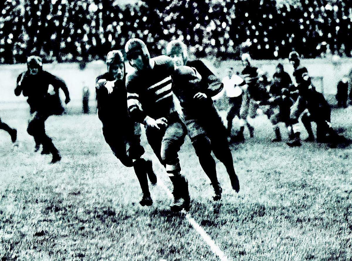 Centre College quarterback Bo McMillin eludes two Harvard defenders on the way to scoring the only touchdown in Centre’s historic 1921 victory over Harvard, then a national football powerhouse.