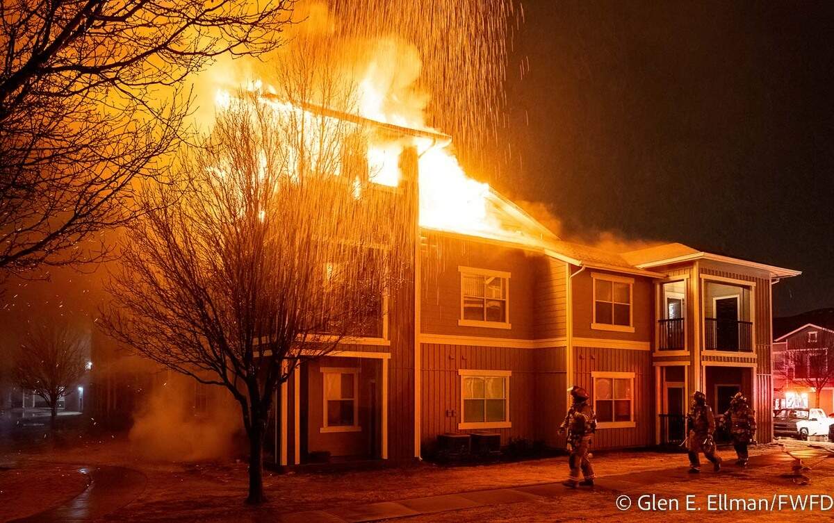 Orange flames billow from the roof of a building.
