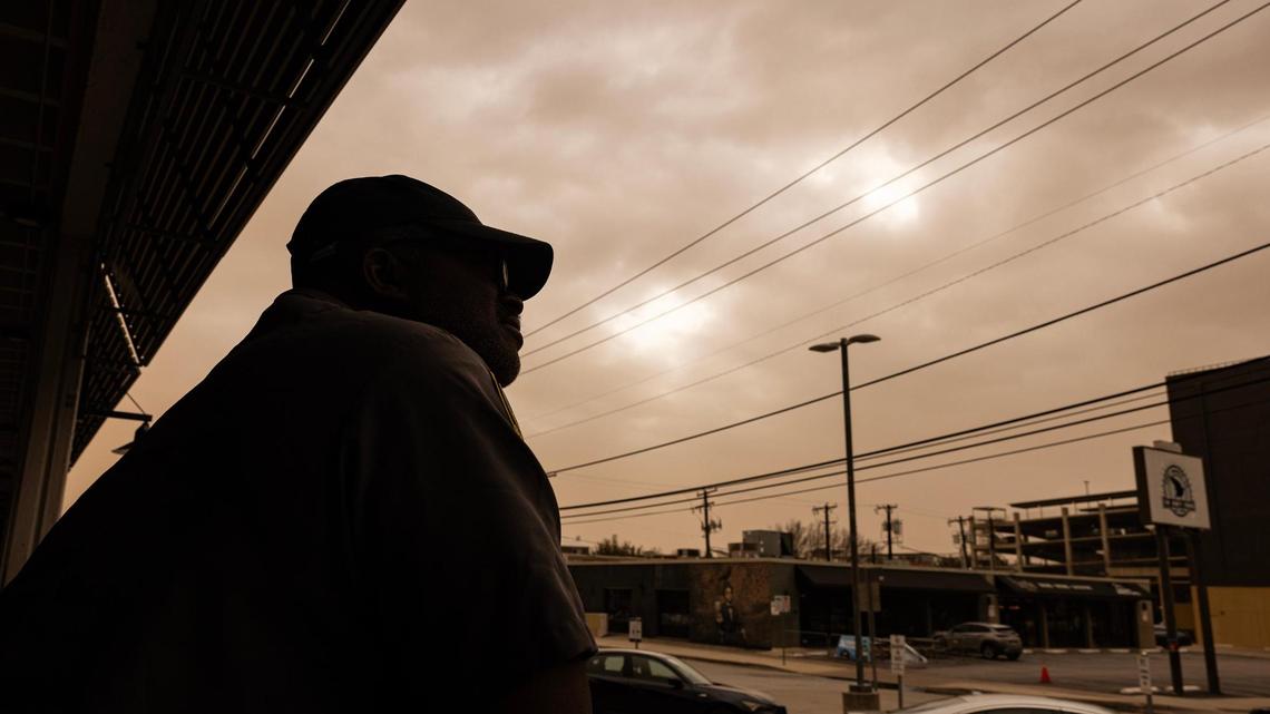 Security guard Shelby Jessie looks up at the dust cloud in the sky while on the job on Foch Street in Fort Worth on Tuesday, March 4, 2025. The dust is coming from West Texas. North Texans can expect visibility to be just a few miles in some areas Tuesday, according to the National Weather Service.