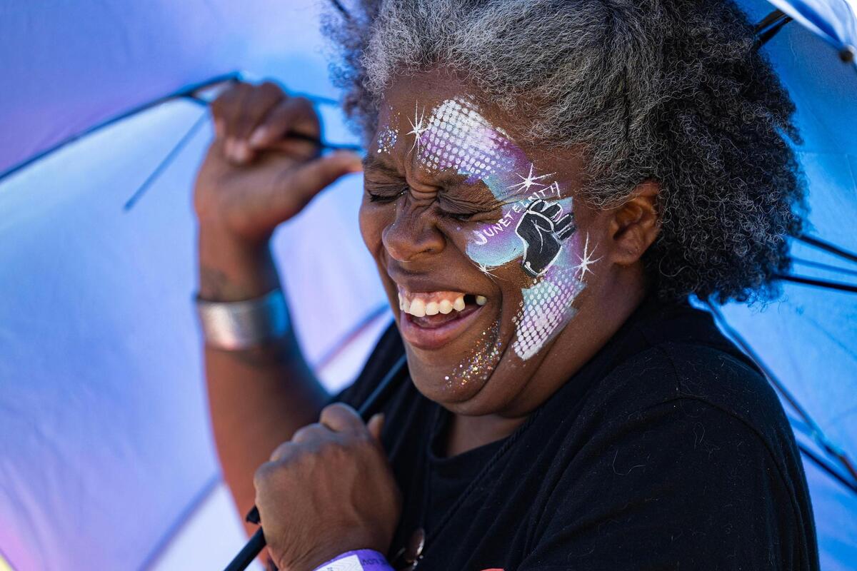 Fort Worth resident Devika Lyles laughs as her umbrella is pulled by the wind while wearing Juneteenth face paint for the Freedom Vibes Juneteenth Block Party in Fort Worth on Saturday, June 21, 2025.
