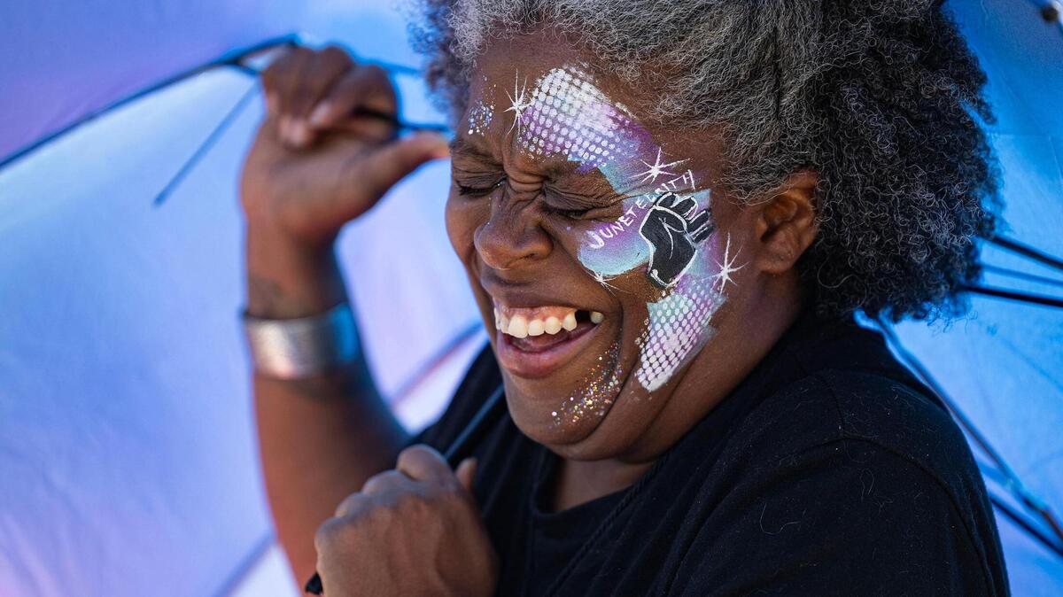Fort Worth resident Devika Lyles laughs as her umbrella is pulled by the wind while wearing Juneteenth face paint for the Freedom Vibes Juneteenth Block Party in Fort Worth on Saturday, June 21, 2025.