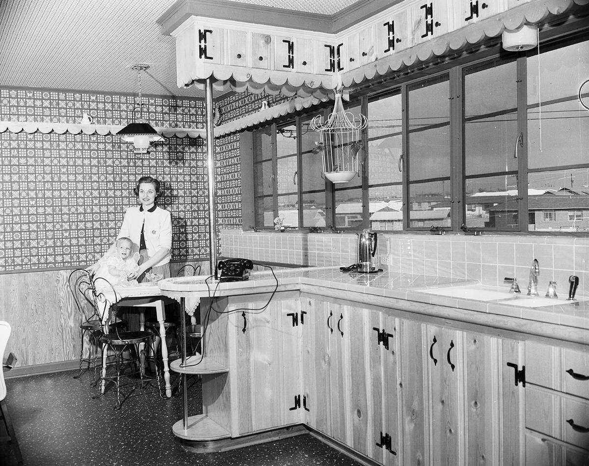 Jan. 18, 1954: Mrs. Jimmie D. Harrington and daughter, Carrie, shown in the kitchen-breakfast area of their new home. Of particular note are the tile features on the drain board and under the steel casement windows, and the cabinets with a blond or natural finish.
