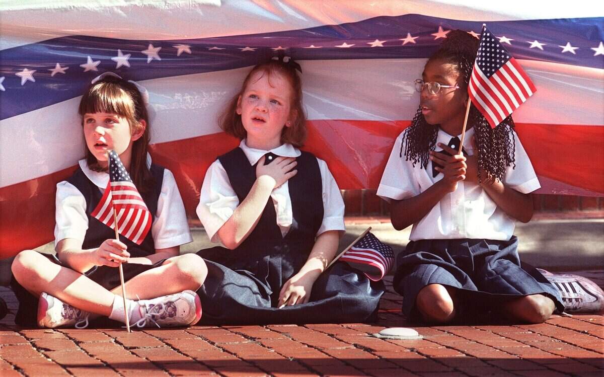 Nov. 11, 1999: Anna Jones, left, Kristen Little and Kimberly Simmons, all 8 years old, of the Harvest Christian School in Fort Worth sit under the reviewing stand and show their patriotism as the Veterans Day parade passes.