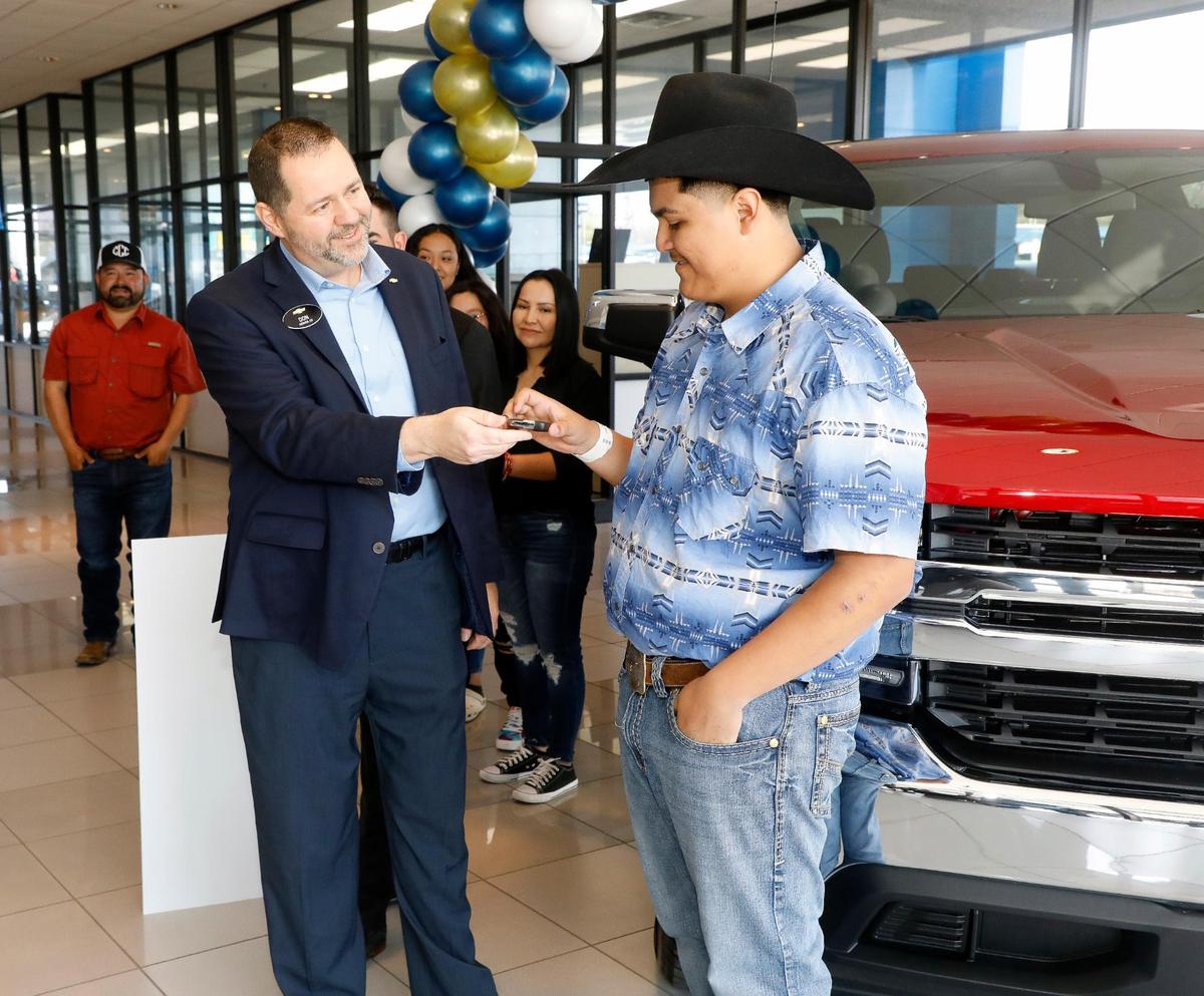 Regional Director for Chevrolet Don Wagner hands over the keys of a new Silverado to Riley Leon, 16, with his family standing in the background, at Bruce Lowrie Chevrolet in Fort Worth, Texas, on Saturday, March 26, 2022. Leon received a new Chevrolet Silverado after the one he was driving was totaled in a tornado.