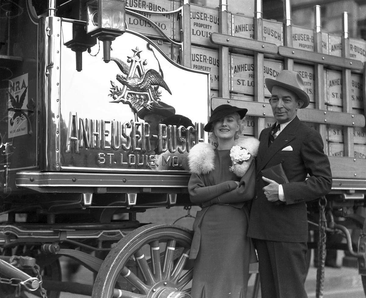 March 20, 1935: An Anheuser-Busch wagon drawn by Clydesdale horses made an appearance at the Stock Show.  Beatrice Brenner, a torch singer with the Johnny Robinson’s Orchestra at Fort Worth’s Blackstone Hotel, rode in the wagon.  She is pictured here with Ben E. Keith, president of Ben E. Keith Co., a regional wholesale distributor of fresh fruits and vegetables and distributor for Anheuser-Busch products. Keith entered the wholesale produce business in 1906 and helped organize the Harkrider-Morrison Co., which became Harkrider-Keith-Cooke Co..  In 1918 Keith purchased controlling interest and was named president.