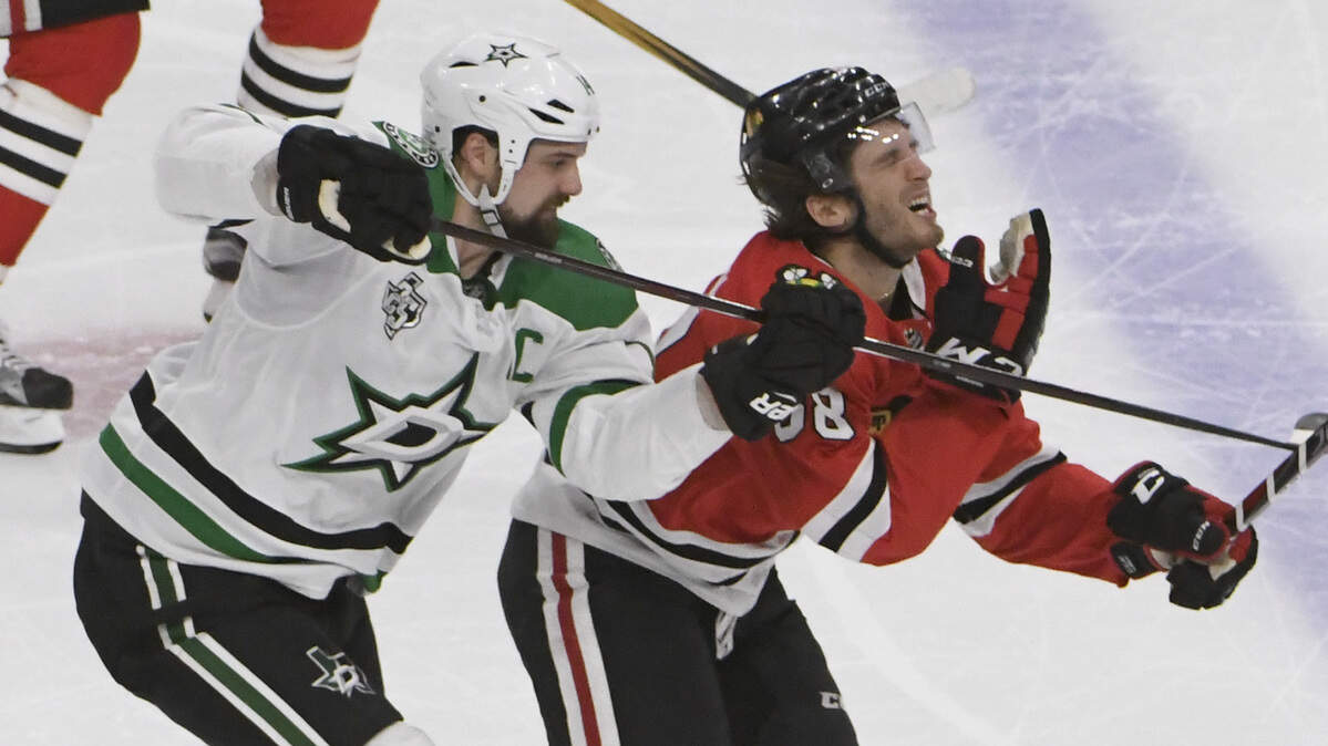 Chicago Blackhawks left wing Ryan Hartman, right, reacts after being hit on the face with a stick by Dallas Stars left wing Jamie Benn, left, during the second period of an NHL hockey game Thursday, Feb. 8, 2018, in Chicago.