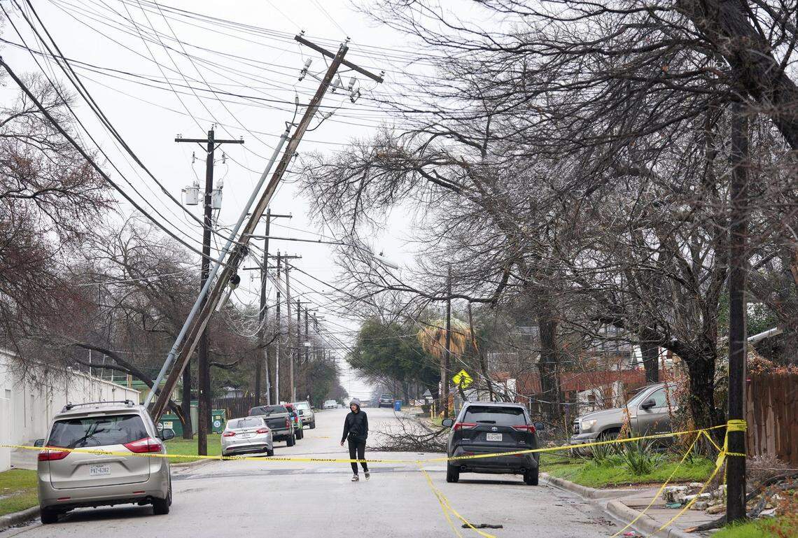Haley Samford walks past a leaning utility pole on Harmon Avenue in Austin, Texas, during a winter storm on Thursday Feb. 2, 2023. Thousands of frustrated Texans shivered in their homes Thursday after more than a day without power, including many in the state capital, as an icy winter storm that has been blamed for at least 10 traffic deaths lingered across much of the southern U.S. (Jay Janner/Austin American-Statesman via AP)