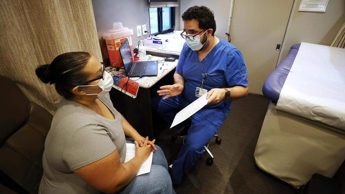 Local vocational nurse Pierre Claros, right, talks to Adriana Salcido-Macias before administrating the Pfizer vaccine in October 2021 at a Texas Health Resources mobile clinic. The health network was nationally recognized for its community involvement.