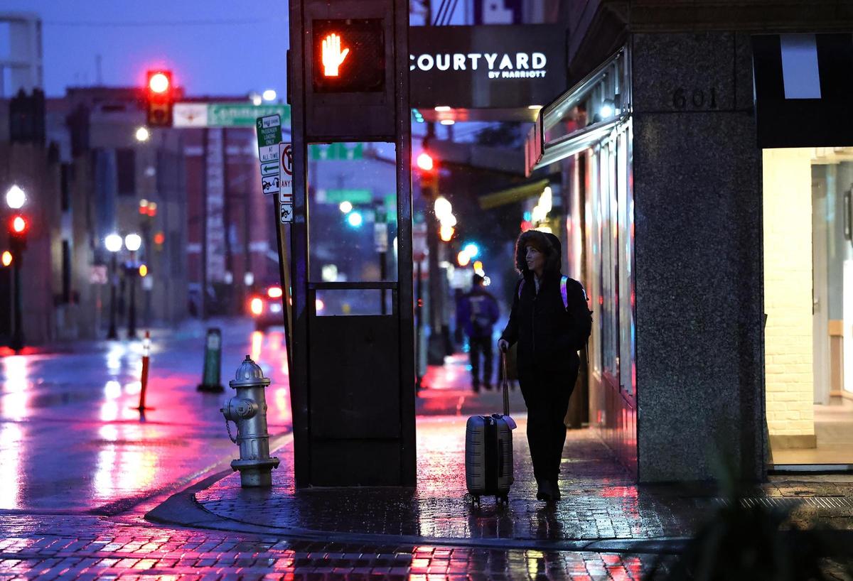 A pedestrian walks in downtown Fort Worth early Thursday morning, Jan. 9, 2025, as snow begins to fall. A winter storm warning is in effect for North Texas.