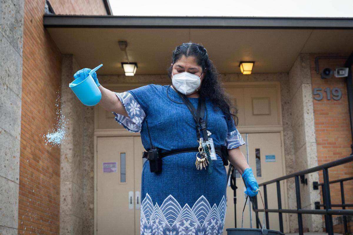 Herminia Armijo pours salt on the walkways in preparation for the winter storm Wednesday, Feb. 2, 2022, at Worth Heights Elementary in Fort Worth.