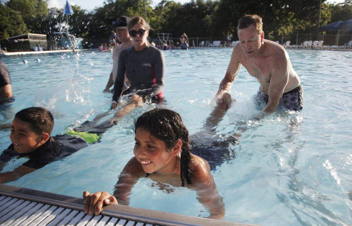 Swim instructors Jane Lacy, left, and Rob Mulqueen teach Jonathan Gomez, 8, and Daniela Duarte, 10, how to kick their legs while swimming at the Forest Park pool in Fort Worth, June 18, 2018.