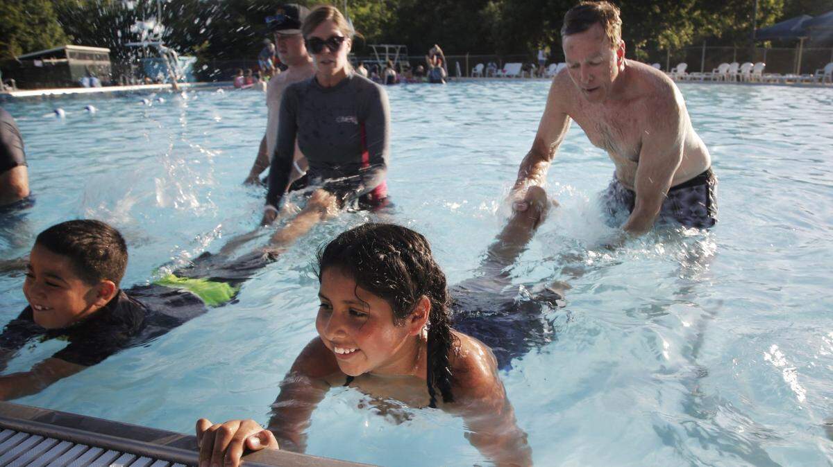 Swim instructors Jane Lacy, left, and Rob Mulqueen, right, teach Jonathan Gomez, 8, Daniela Duarte, 10, how to use kick their legs while swimming at the Forest Park Pool in Fort Worth, Monday, June 18, 2018.