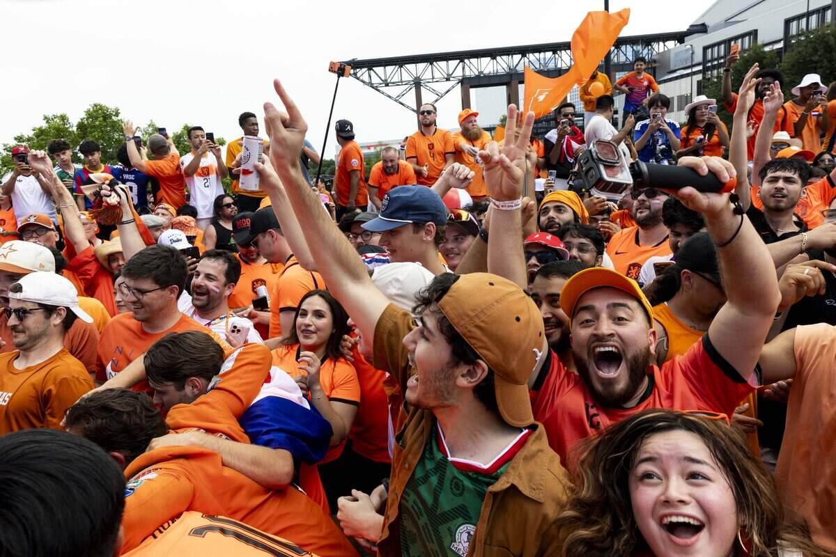 Netherlands soccer fans dance in the streets as the Orange Bus arrives to Dallas Stadium ahead of the FIFA World Cup match against Japan on Sunday, June 14, 2026 in Arlington, Texas.