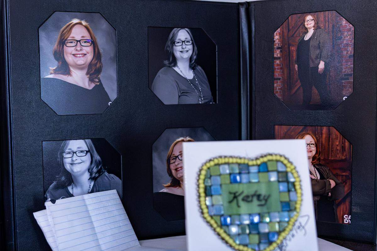 A collage of photos of Katey Kirkland in a black stand. A piece of art and folded note sit in front of the photos. 