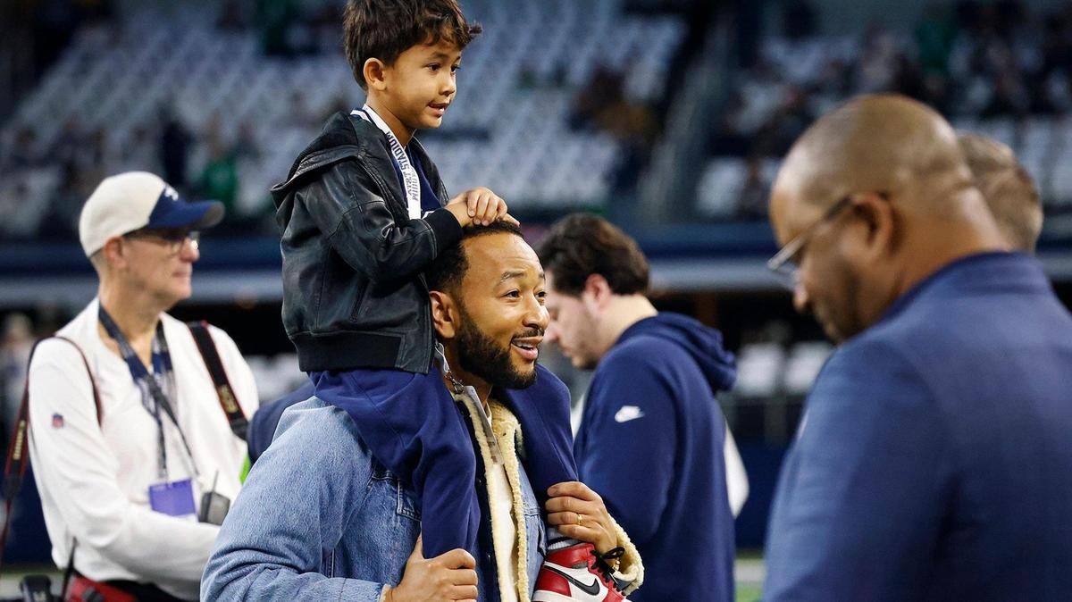 John Legend and his son, Miles, watch the Dallas Cowboys warmup from the sidelines prior to kickoff against the Philadelphia Eagles on Sunday, December 10, 2023, at AT&T Stadium in Arlington.