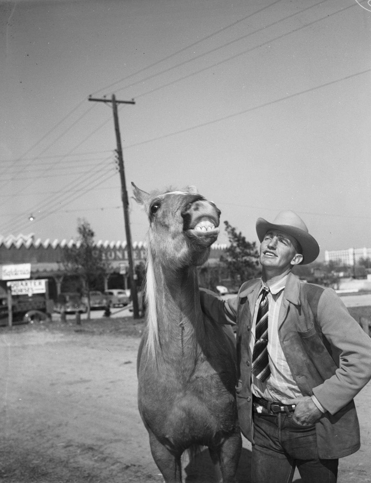 March 8, 1945: Pat Henry with a laughing horse named Golden Lurce. “The smirking Palomino is a young stock horse owned by Mrs. Lucille L. Cofield of Tulsa, Oklahoma. Mr. Henry is Golden Lucre’s trainer.” Behind the horse and trainer is a store called Pioneer Palace.