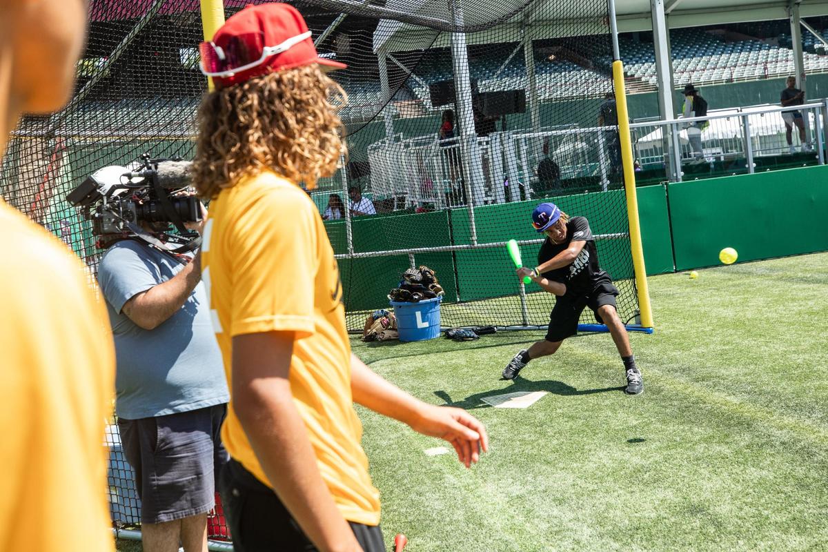 Vincent Hood, 15, left, swings the bat during the All-Star Village hard hat tour on Thursday, July 11 at the Choctaw stadium in Arlington. Fans can play baseball with friends and family as well as practice their pitch and batting.