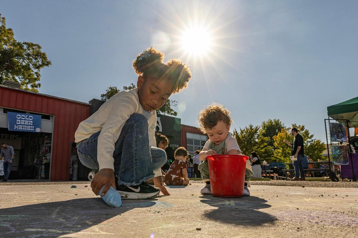 Kindly Davis, 6, and Maddox McAllister, 1, draw on the sidewalk during the Arts Goggle event on Magnolia Avenue in Fort Worth on Saturday, Oct. 19, 2024.