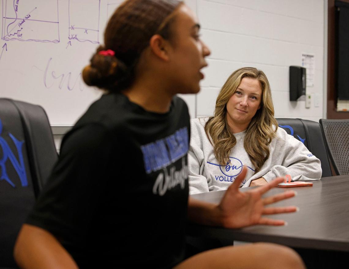 Head coach, Brianne Barker Groth, listens as Sydnee Peterson is interviewed during volleyball practice at Byron Nelson High School in Trophy Club Texas, Wednesday, Sept. 25, 2024.