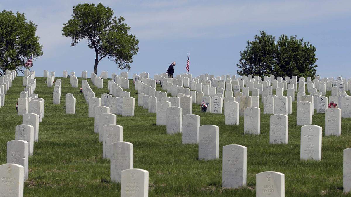 A man stands alone amidst the headstones at Fort Snelling National Cemetery, Friday, May 24, 2013 in Minneapolis, as visitors got an early start to the Memorial Day weekend. (AP Photo/Jim Mone) ORG XMIT: MP101