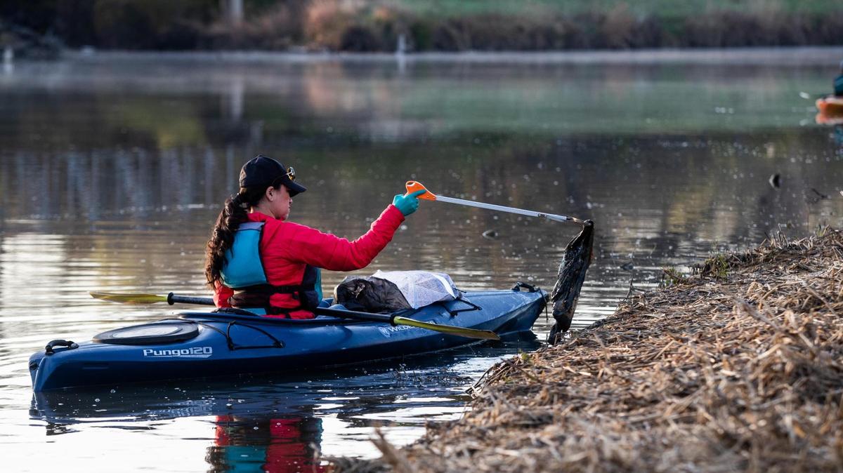 A volunteer in a kayak scoops up trash along the Trinity River during the Great American Cowtown Cleanup on March 20, 2021. This year’s Cowtown Cleanup is scheduled for March 26 from 8-11 a.m.