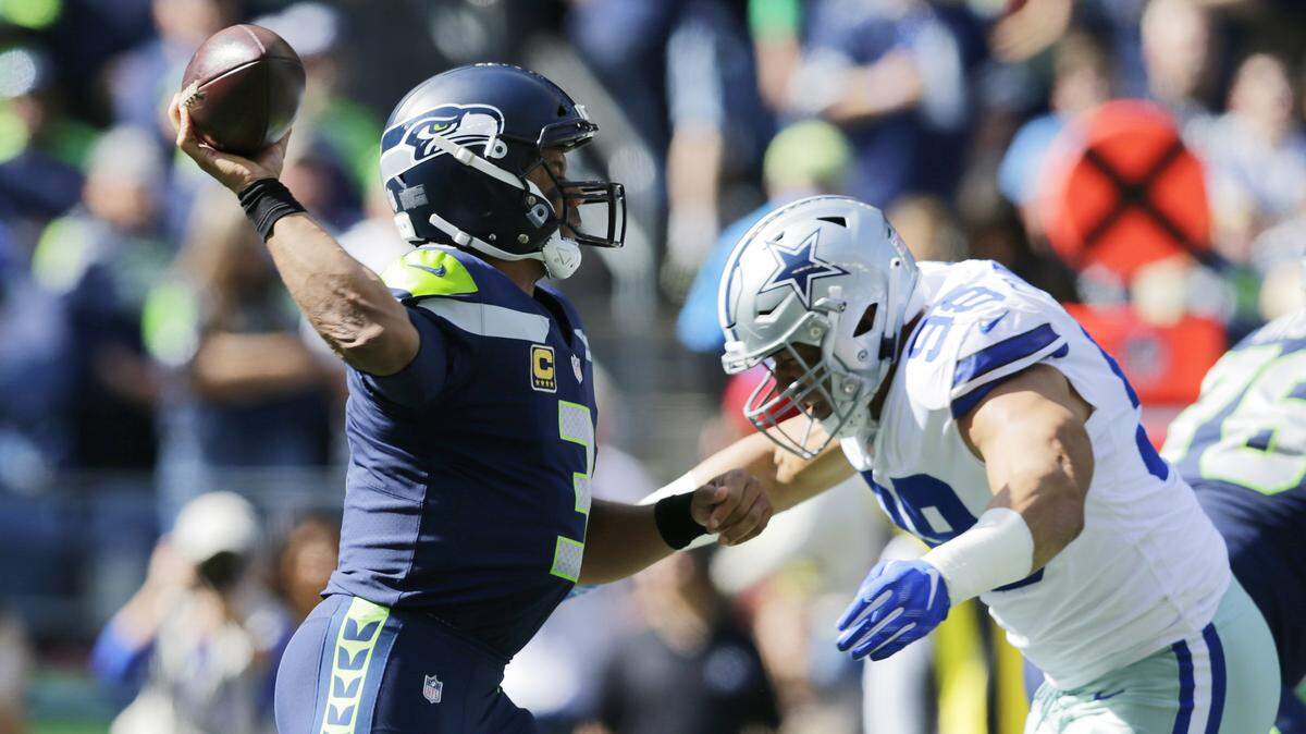 Seahawks quarterback Russell Wilson prepares to pass as Cowboys defensive end Tyrone Crawford, right, moves in for a hit during the first half Sunday. Crawford was flagged for roughing the passer because officials said he landed with his body weight on Wilson. The Cowboys lost 24-13.