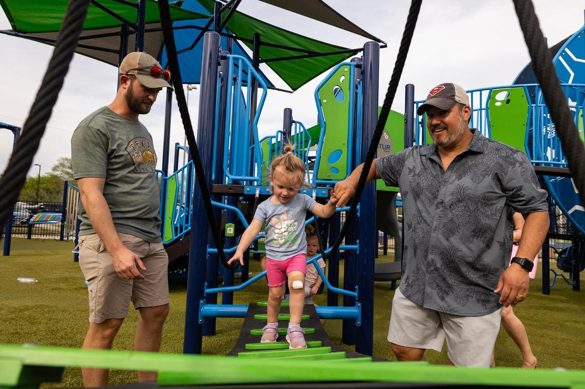 Denton resident Max Brown, left, helps his daughter Ava, 2, with his father-in-law Colin Galdo play on the bridge in Harmon Park in Decatur on March 29, 2025. Brown said he welcomes growth but hopes the city implements more resources and amenities to accommodate all of its residents, old and new. Brown also mentioned the only grocery store in the area is a Walmart.