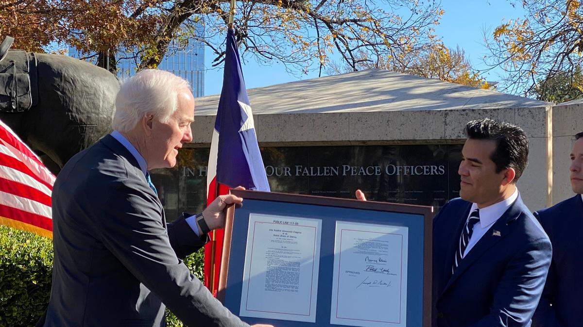 Sen. John Cornyn, left, presented a copy of a bill that protects federal officers serving abroad to Victor Avila of Southlake.